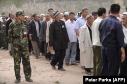 Китайский военный наблюдает за уйгурами на похоронах убитого полицейского, 2008 год, После массовых антиправительственных протестов 2008-2009 годов Китай решил взять уйгуров под тотальный контроль