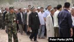 FILE: Ethnic Uighurs, some wearing white flowers, gather before an official ceremony.