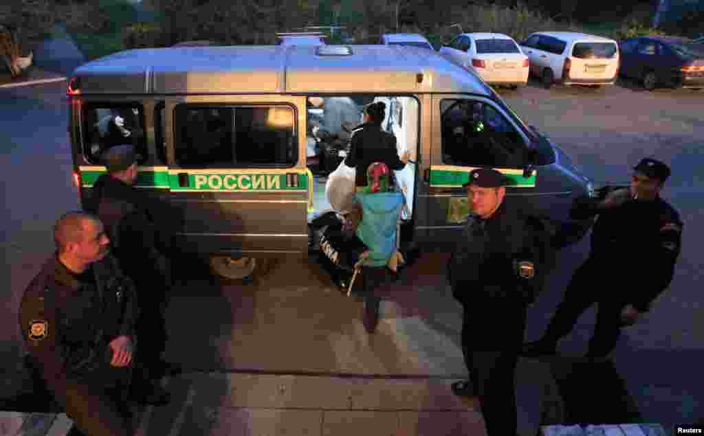 Migrants board a police van before being deported from Russia.