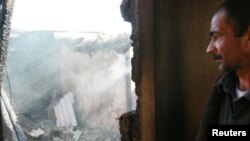 A man stands in the burned ruins of his house in Maevka on April 20.