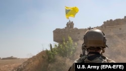 Militari din Forţele Democratice Siriene dând jos un drapel al YPG