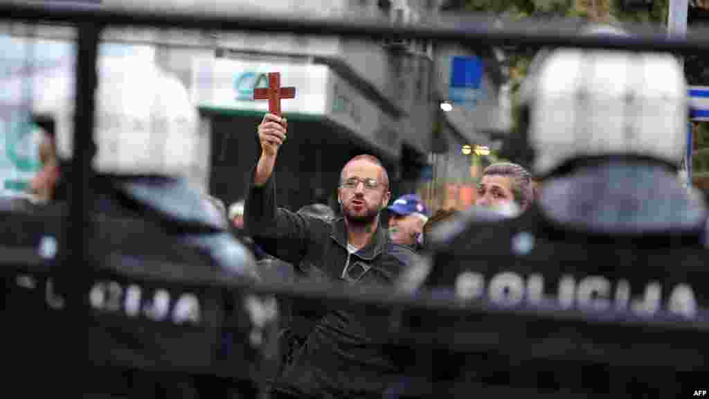 A Serbian ultranationalist waves a cross in front of riot police as he takes part in a protest against an exhibition of controversial photographs by Swedish artist Elisabeth Ohlson Wallin in Belgrade on October 3. The Serbian Interior Ministry banned a gay-pride parade for security reasons for the second year running after ultranationalists threatened the march and the influential Serbian Orthodox Church condemned it. (AFP/Andrej Isakovic)