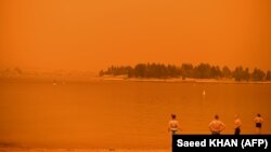 شماری از مردم جیندابین در نیو ساوت ولز استرالیا، در زیر آسمانی که به خاطر دود ناشی از آتش‌سوزی قرمز شده، خود را خنک می‌کنند. ۴ ژانویه ۲۰۲۰