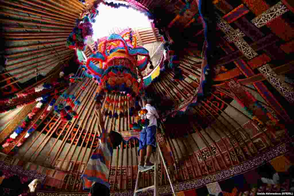Astara's son Erhan hangs the "chandelier," a woven decoration hanging below a skylight.