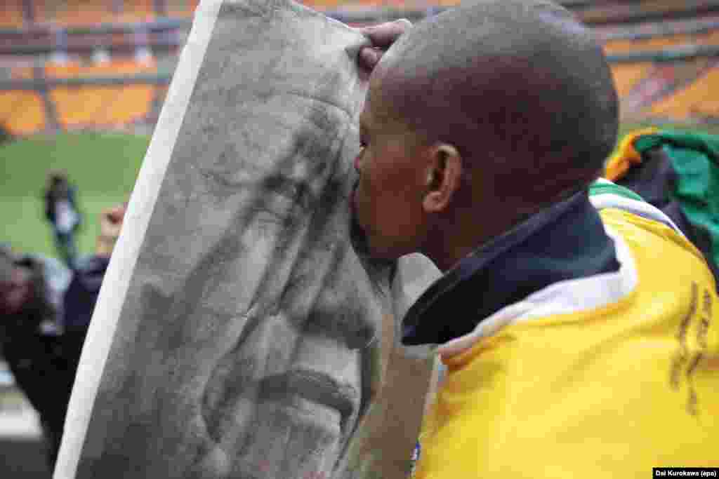  Мальчик целует портрет бывшего президента ЮАР Нельсона Манделы. Йоханнесбург, 10 декабря 2013 года. Мандела умер 5 декабря. 