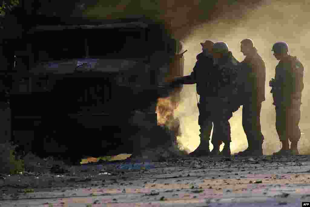 Ukrainian soldiers check a smoldering army truck after an overnight bombing attack at a Ukrainian Army checkpoint on the outskirts of the key southeastern port city of Mariupol. (AFP/Philippe Desmazes)