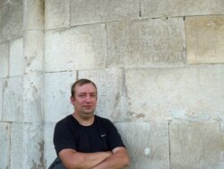 Історик В’ячеслав Корнієнко біля графіті на стіні (зовнішній) храму святого Пантелеймона