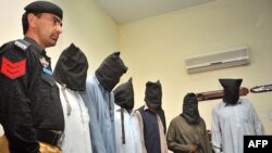 FILE: A Pakistani policeman stands guard alongside suspects who allegedly killed Sikh politician Sardar Soran Singh during a press conference after their arrest in Peshawar, on April 25.