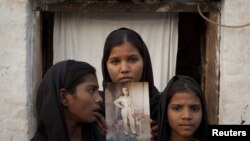 The daughters of Christian woman Asia Bibi pose with an image of their mother while standing outside their residence in Sheikhupura in the eastern Punjab Province.