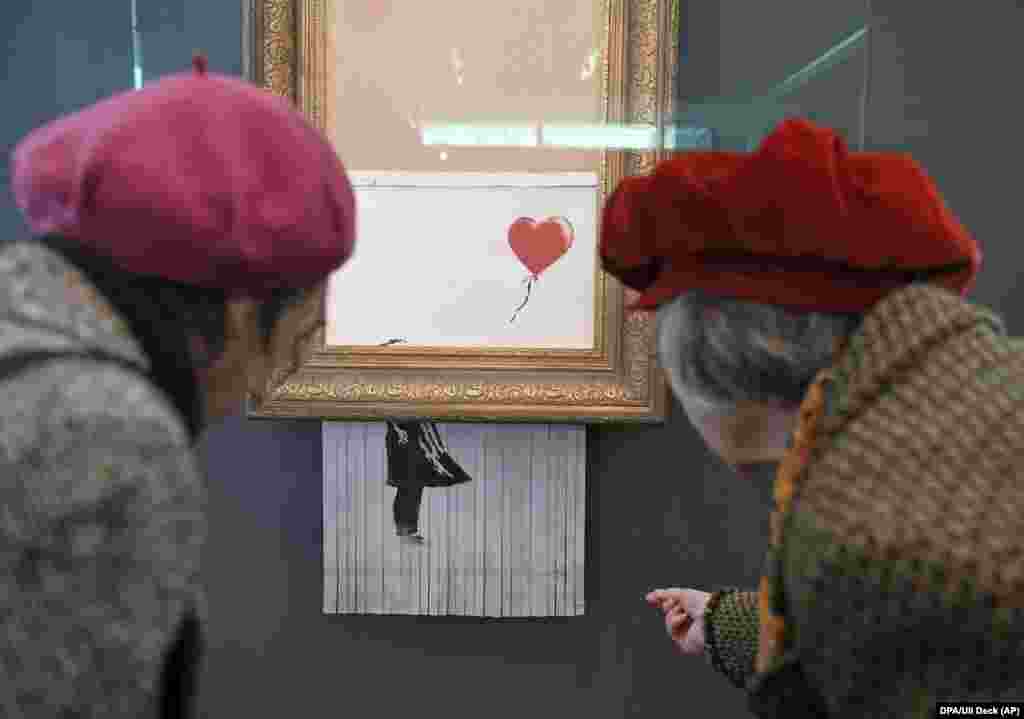 Two women look at the shredded Banksy painting Love Is In The Bin at the Frieder Burda Museum in Baden-Baden, Germany. (dpa/Uli Deck)