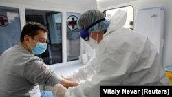 Медик в защитном костюме готовится к забору крови пациента на анализ. Калининград, 20 мая 2020 года.