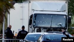 Сотрудники сил безопасности Франции возле грузовика на следующий день после того, как он въехал в толпу, собравшуюся на Английской набережной во французском городе Ницца 14 июля 2016 года.