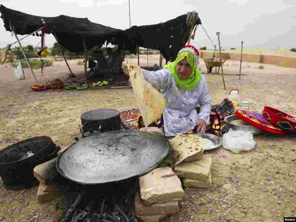 A woman from the Bakhtiari tribe cooks bread in front of the Chogha Zanbil Ziggurat, near Susa, in Iran&#39;s Khuzestan Province. (REUTERS/Raheb Homavandi)