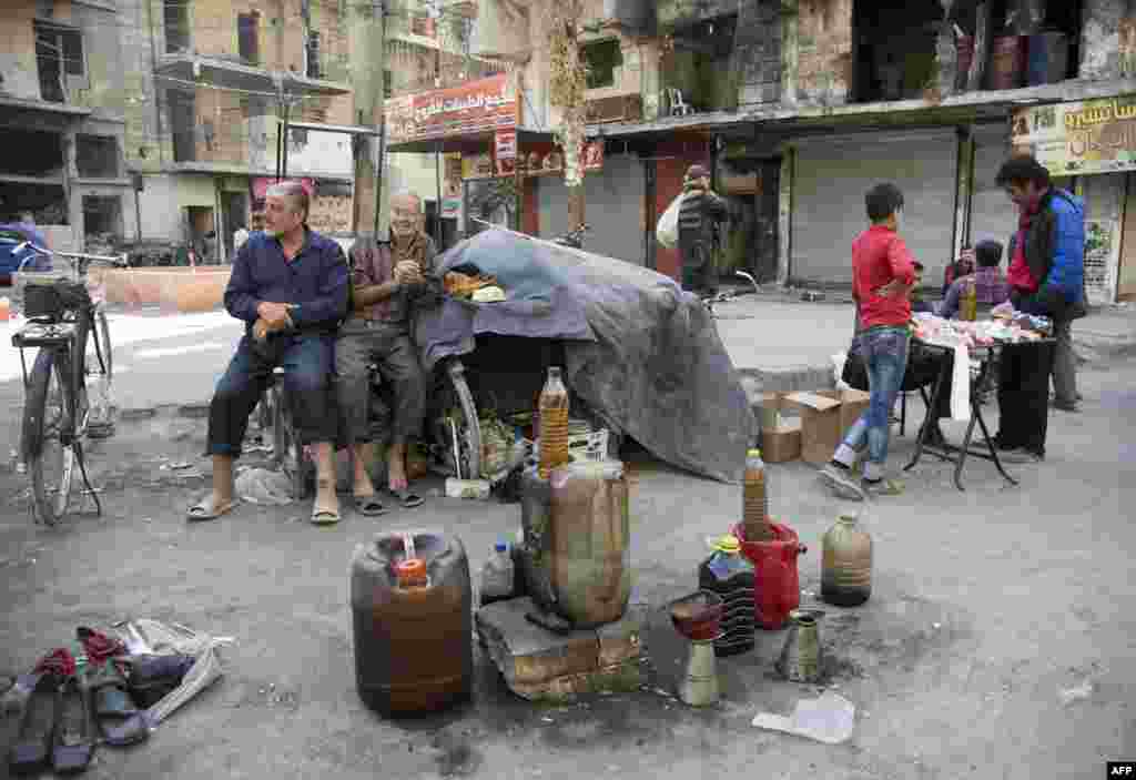 Syrian men sell fuel produced from plastic in the rebel-held side of the embattled city of Aleppo. (AFP/Karam al-Masri)