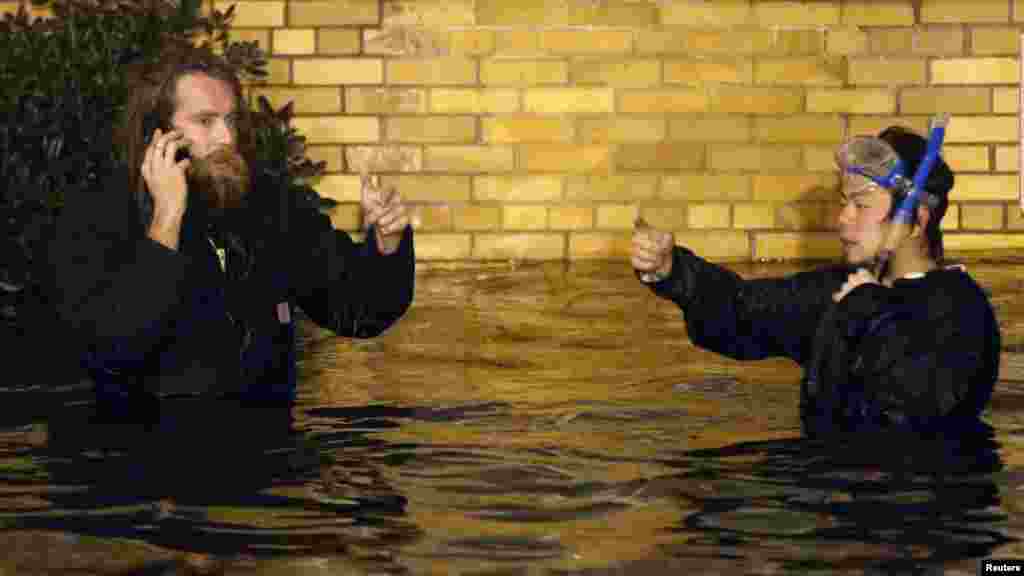 Два жителя Нью-Йорка с трубкой для подводного плавания идут вброд по затопленным улицам Бруклина.