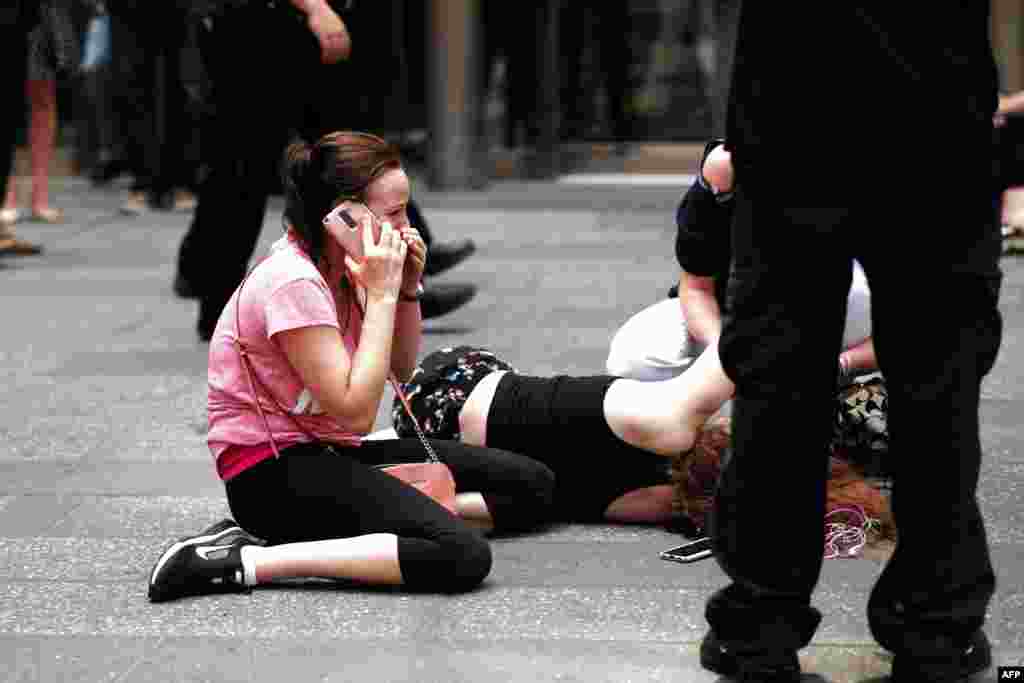 Një grua duke bërë një telefonatë, ndërsa të tjerët mundohen t&#39;i ndihmojnë një gruaje të lënduar, pasi një makinë qëllimshëm u fut në mes të këmbësorëve në Times Square të Nju Jorkut më 18 maj.