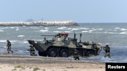 Российские морские пехотинцы выходят на берег рядом с бронетранспортером БТР-82А во время учений «Центр-2019» на полигоне «Турали» на побережье Каспийского моря. Дагестан, Россия, 20 сентября 2019 года