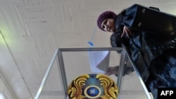 Женщина опускает бюллетень в избирательную урну на участке в день выборов в Казахстане.