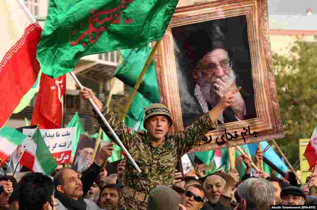 Iranians hold pictures of Supreme Leader Ayatollah Ali Khamenei and wave national flags during a rally in Tehran to show their support of the Islamic republic and to condemn recent violent protests following a surprise fuel-price hike in the country. (epa-EFE/Abedin Taherkenareh)