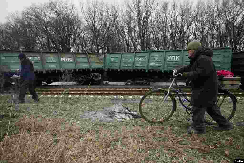 People walk past a train that was derailed after a blast on a rail track in the rebel-controlled town of Yasynuvata, near Donetsk, in Ukraine. (Reuters/Alexander Ermochenko)