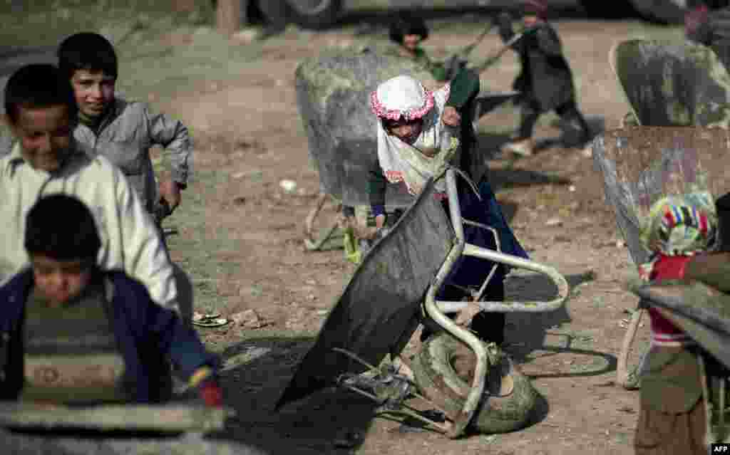 An Afghan girl struggles to handle a wheelbarrow as she waits for food donations from the World Food Program in Kabul. (AFP/Johannes Eisele)