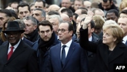 German Chancellor Angela Merkel (right) waves while taking part with French President Francois Hollande (center) in a rally in Paris on January 11.