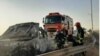 Emergency workers remove a car which exploded into flames after Iranian police reportedly opened fire on it. Three Afghan migrants died in the incident. 