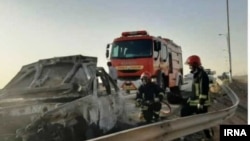 Emergency workers remove a car which exploded into flames after Iranian police reportedly opened fire on it. Three Afghan migrants died in the incident. 