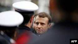 French President Emmanuel Macron speaks with policemen during a commemorative ceremony to mark the third anniversary of the attack on Charlie Hebdo magazine in Paris.