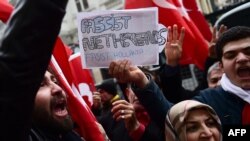 Protesters shout slogans and wave Turkish national flags in front of the Dutch Consulate on March 12, 2017 in Istanbul.