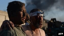 Мужчина ведет пожилого человека, раненного в резульате атаки смертника. Кабул, 2 июоя 2013 года. Иллюстративное фото.