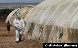Сотрудник Сирийской гражданской обороны ("Белые каски") проводит санобработку палаток в лагере для беженцев в зоне Идлиба. 28 марта