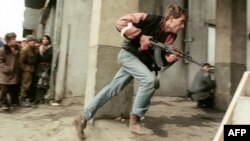 An armed civilian chases the supposed Securitate secret police agents during street fighting in downtown Bucharest in December 1989.