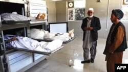 Men stand next to the bodies of the workers who were killed by Taliban insurgents in the western Herat Province on August 26.
