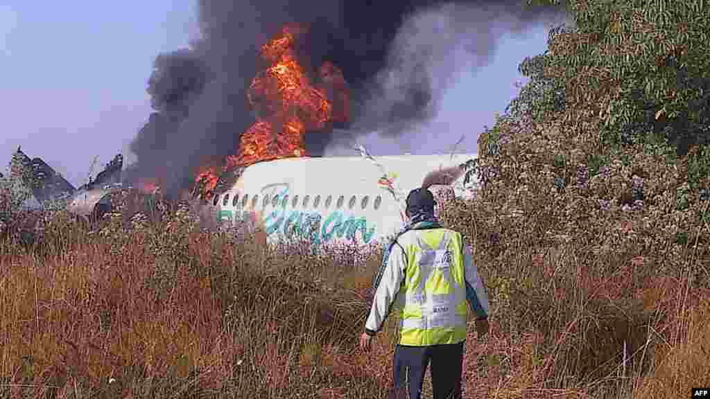 A man walks near the fuselage of an Air Bagan passenger plane after it crashed near Heho airport in Burma&#39;s eastern Shan state on December 25, killing two people and injuring 11.