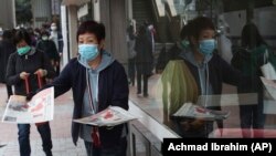 A women wearing a protective face mask delivers a leaflet on coronavirus in Hong Kong on January 24.