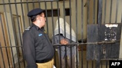 A Pakistani police officer speaks to a suspect in connection with the murders of three homosexual men, at a police station in Lahore in 2014.