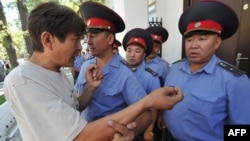 A demonstrator argues with police officers in front of the Belarusian Embassy in Bishkek, Kyrgyzstan in 2012.