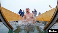 Окунающийся в воду мужчина в день православного Крещения. Архивное фото.
