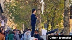 Протест девушки без платка, стоящей по улице Энгелаб в Тегеране, против исламского дресс-кода в Иране