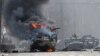 UKRAINE – This photograph taken on February 27, 2022 shows a Russian Armoured personnel carrier (APC) burning next to unidentified soldier's body during fight with the Ukrainian armed forces in Kharkiv