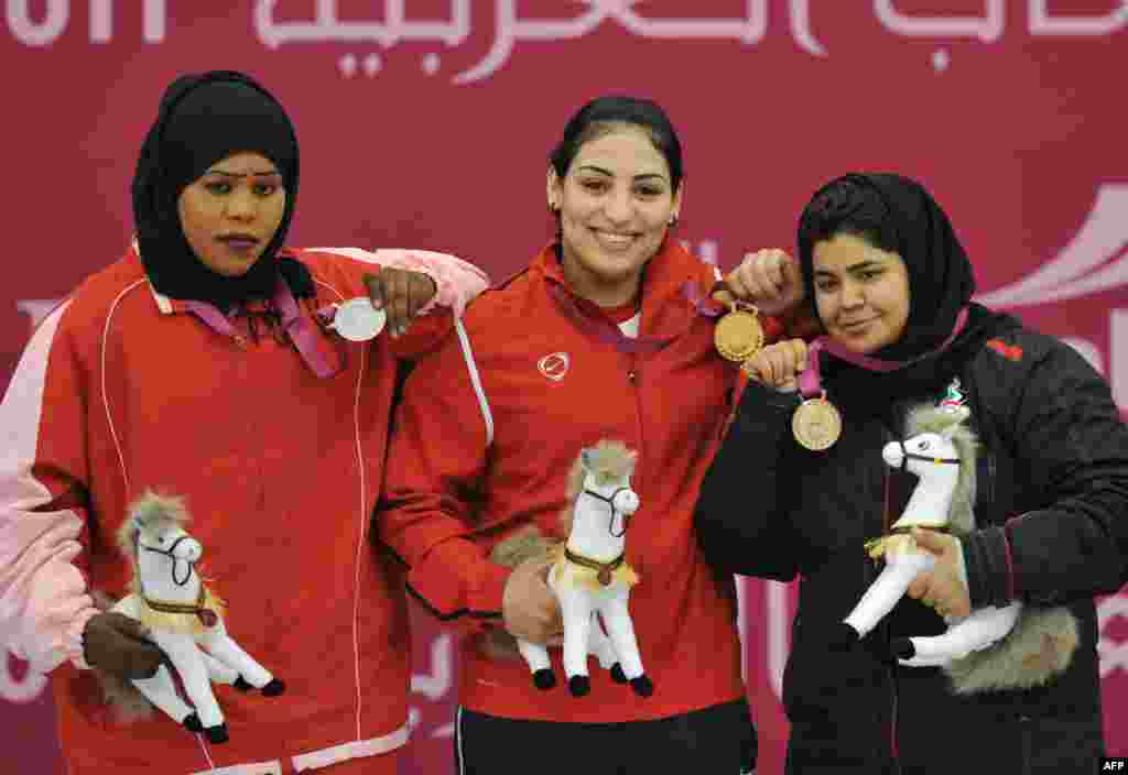 The United Arab Emirates&#39; Yasmin Abbas (right) celebrates her bronze medal in weightlifting in Qatar in December. The UAE has been cleared to send a team to the London Olympics, the first team to compete in Islamic dress.