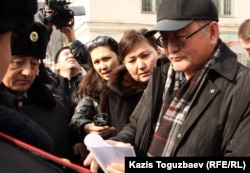Главный редактор газеты "Жас Алаш" Рысбек Сарсенбай читает повестку в суд, которую ему после пресс-конференции вручили полицейские. Алматы, 27 февраля 2012 года.