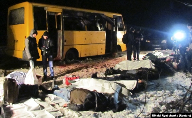 Разследващи работят около пътнически автобус, попаднал под обстрела на проруски сепаратисти в района на контролно-пропускателен пункт на украинските сили близо до град Волноваха в Донецка област, 13 януари 2015 г.