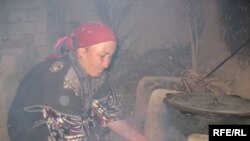 A Tajik woman cooks food over an open fire due to lack of electricity.