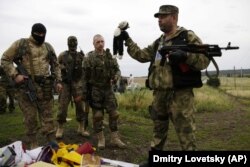Бойовик російських гібридних сил тримає іграшку, виявлену на місці падіння уламків «Боїнга», збитого російською установкою «Бук», в результаті чого загинуло 298 людей, в тому числі 80 дітей. Донеччина, неподалік села Грабове, 19 липня 2014 року