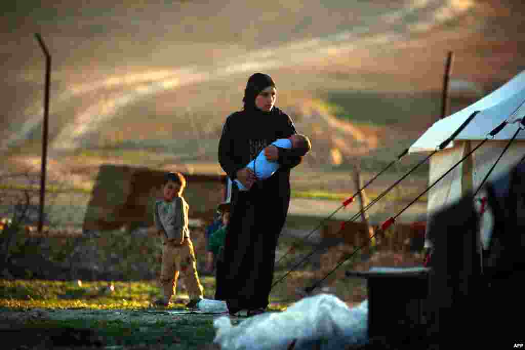 A Syrian woman carries her child at a temporary refugee camp, some 50 kilometers north of the Islamic State extremist group&#39;s stronghold in Raqqa. (AFP/Delil Souleiman)