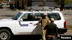 Lucrători ai primăriei din Luhansk se fotografiază lângă un vehicol al OSCE, vineri 25 aprilie, 2014