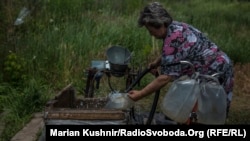 Жінка набирає воду біля свердловини в Красногорівці