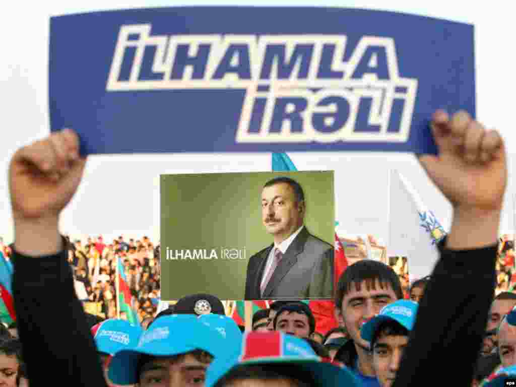 Caption: epa01519130 Azeri people hold placards and posters reading Ilham go forward in front of pre-electoral posters showing candidate and Azerbaijan present President Ilham Aliyev during a rally supporting his candidacy at the upcoming president elections in Sumgait, some 30km from Baku, Azerbaidjan, 13 October 2008.